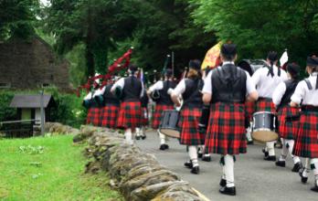 Photos of pipers marching over bridge playing the bagpipes