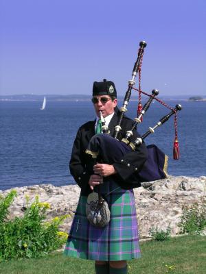 piper playing bagpipes by the sea in Scotland